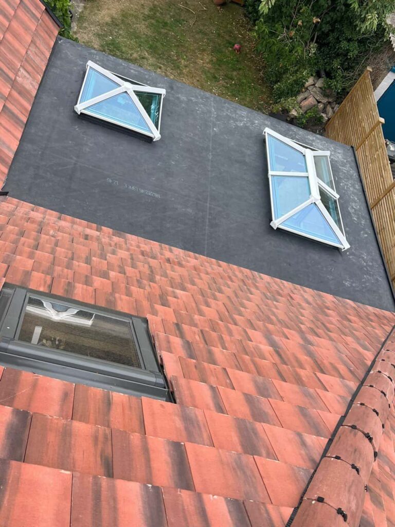 This is a photo taken from the roof ridge looking down a tiled pitched roof on to a flat roof. Works carried out by Saffron Walden Roofing Repairs